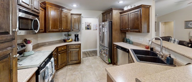 kitchen with appliances with stainless steel finishes, dark brown cabinetry, lofted ceiling, and sink