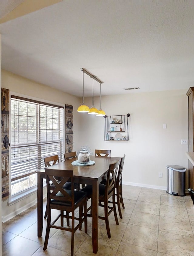 tiled dining area with a textured ceiling and rail lighting