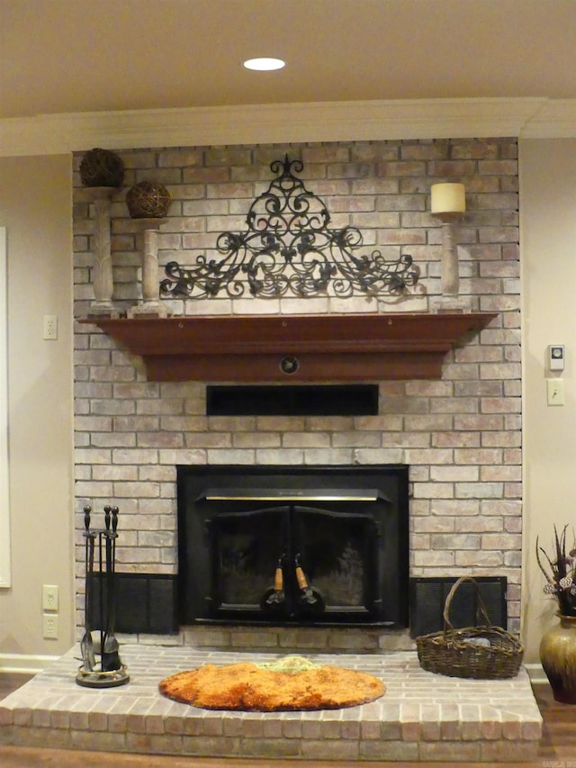 room details with a brick fireplace, hardwood / wood-style flooring, and ornamental molding