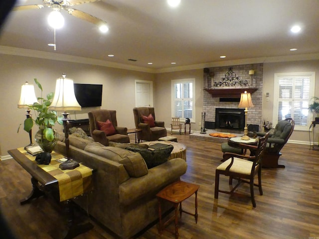 living room with ornamental molding, a brick fireplace, ceiling fan, and dark hardwood / wood-style floors