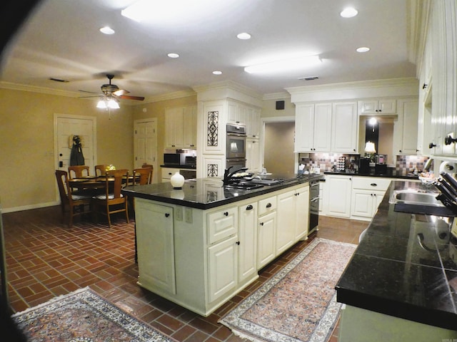 kitchen featuring white cabinets, a center island, ceiling fan, double oven, and sink