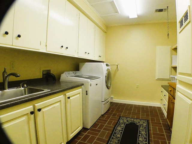 clothes washing area featuring sink, washer and dryer, and cabinets