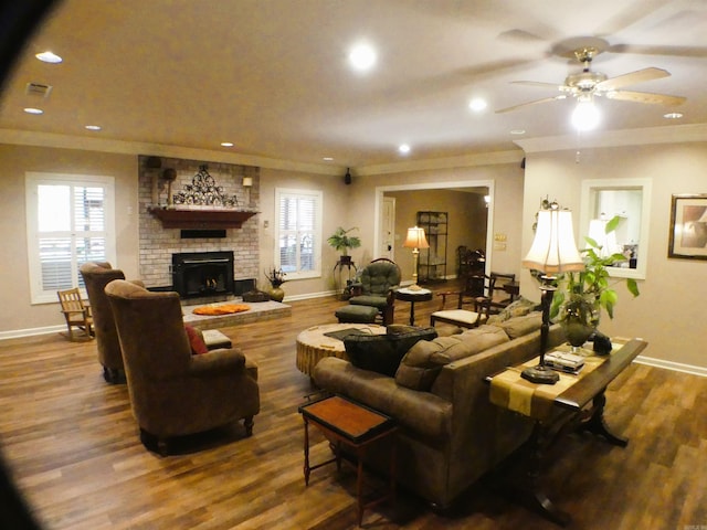 living room featuring wood-type flooring, a fireplace, ornamental molding, and ceiling fan