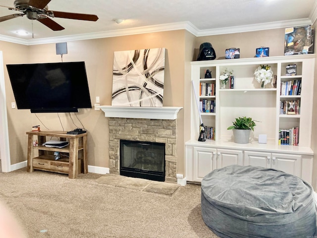 carpeted living room featuring ornamental molding, ceiling fan, and a stone fireplace