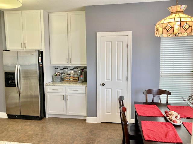 kitchen featuring stainless steel refrigerator with ice dispenser, decorative light fixtures, tasteful backsplash, and white cabinetry