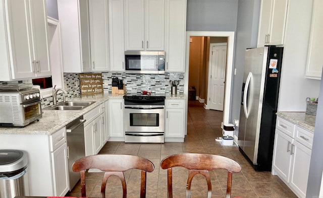 kitchen featuring decorative backsplash, stainless steel appliances, white cabinets, and sink