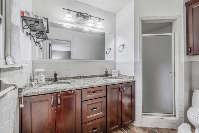 bathroom with tile walls, vanity, an enclosed shower, and toilet