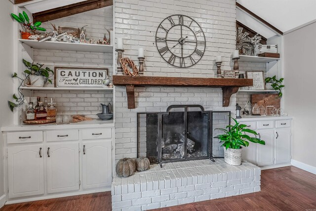 living room featuring a brick fireplace, lofted ceiling with beams, and dark hardwood / wood-style flooring