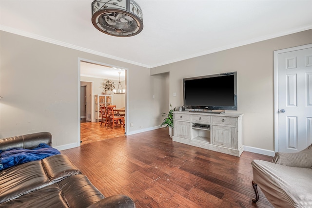 living room featuring a chandelier, dark wood-type flooring, and crown molding