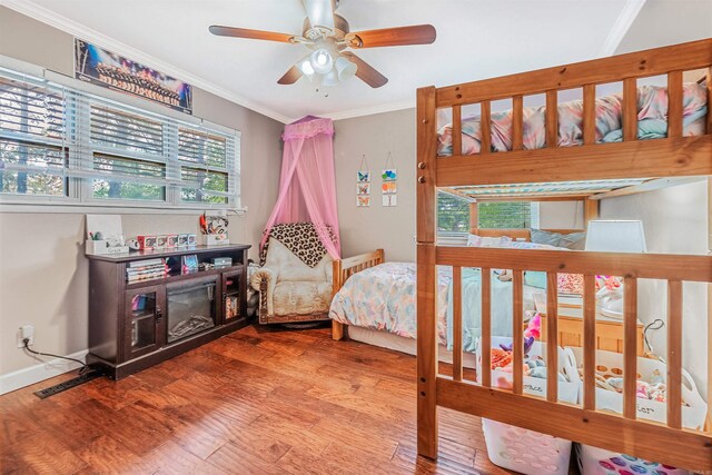 bedroom featuring ceiling fan, wood-type flooring, crown molding, and multiple windows