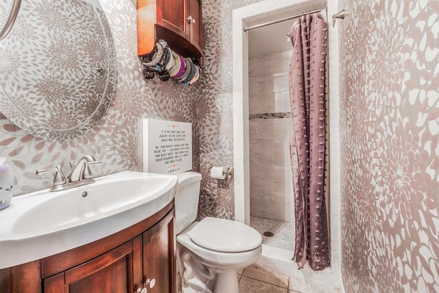 bathroom featuring tile patterned flooring, walk in shower, vanity, and toilet