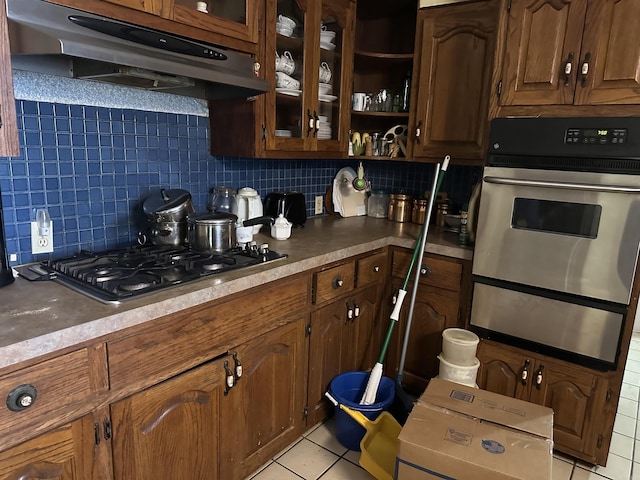 kitchen featuring black gas cooktop, tasteful backsplash, light tile patterned floors, and oven