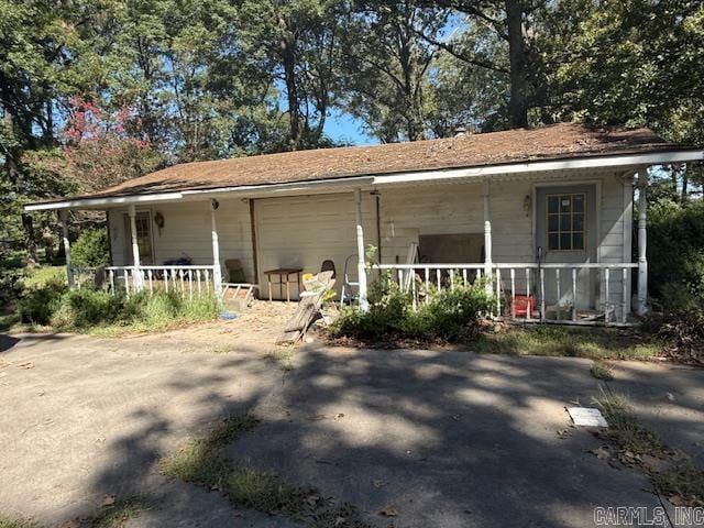 back of property with covered porch and a garage