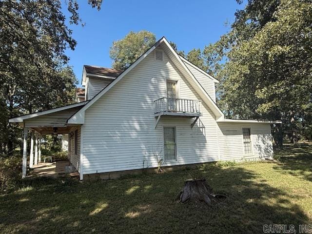 back of house with a balcony and a yard