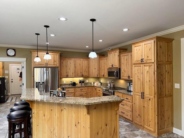 kitchen featuring hanging light fixtures, stone countertops, stainless steel appliances, a kitchen bar, and a kitchen island with sink