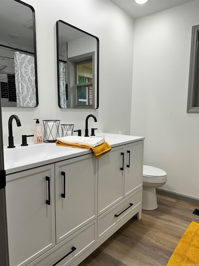 bathroom with hardwood / wood-style floors, vanity, and toilet