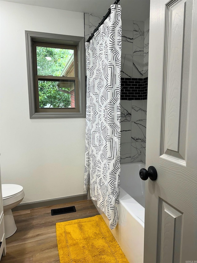 bathroom with hardwood / wood-style floors, toilet, and shower / bath combo