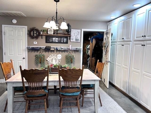 dining space featuring dark carpet and a notable chandelier