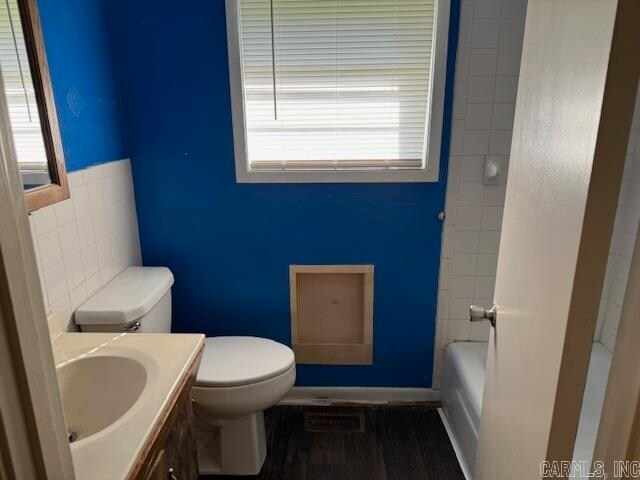 bathroom with tile walls, vanity, a healthy amount of sunlight, and toilet