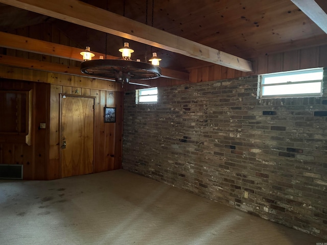 basement with a healthy amount of sunlight, carpet flooring, wood walls, and brick wall