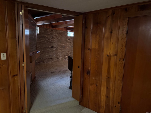 hall with wood walls, light colored carpet, and brick wall