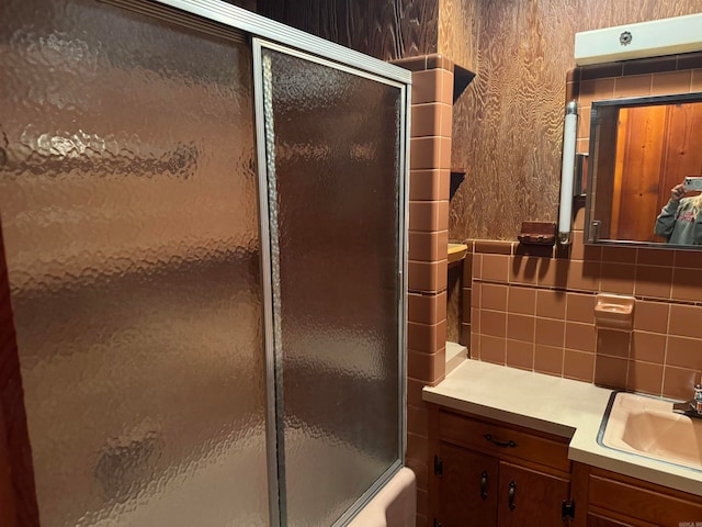 bathroom featuring shower / bath combination with glass door, vanity, and tile walls