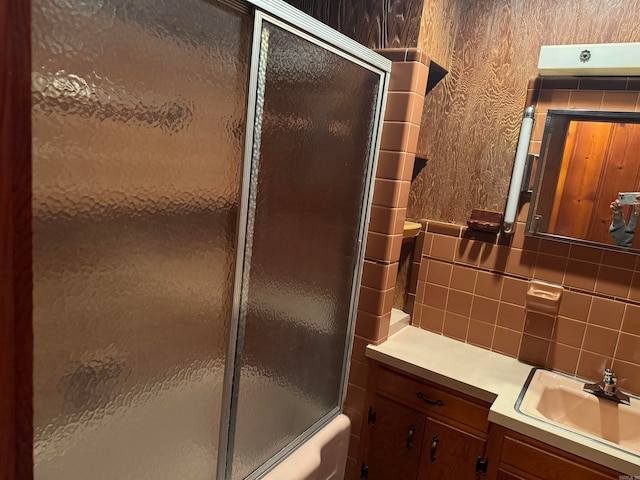 bathroom with enclosed tub / shower combo, vanity, and tasteful backsplash