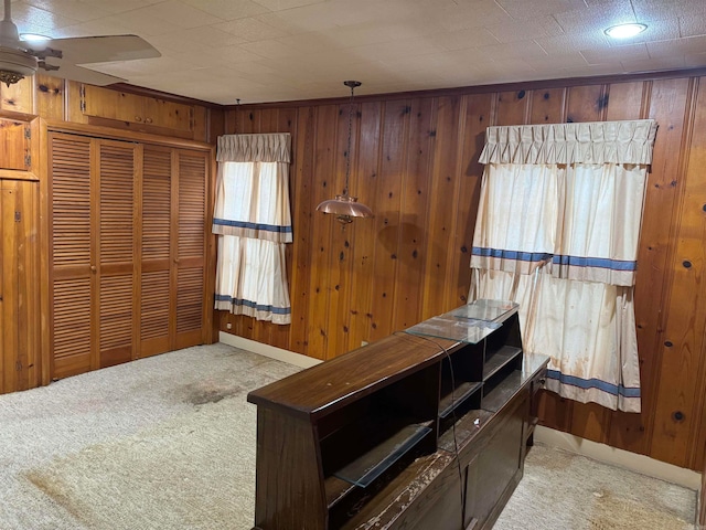 unfurnished office with wooden walls, ceiling fan, and light colored carpet