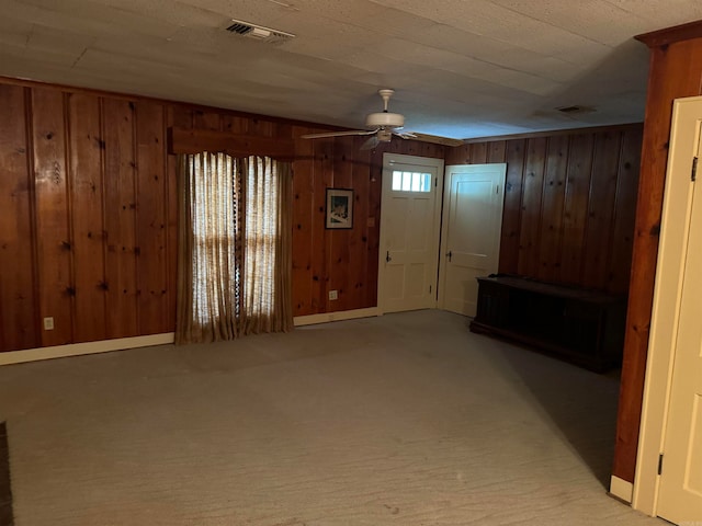 unfurnished living room with ceiling fan, plenty of natural light, and wood walls