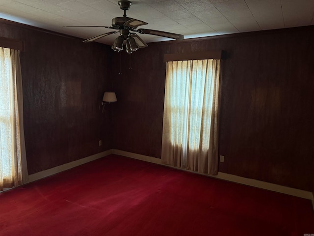 spare room with carpet floors, wooden walls, and ceiling fan