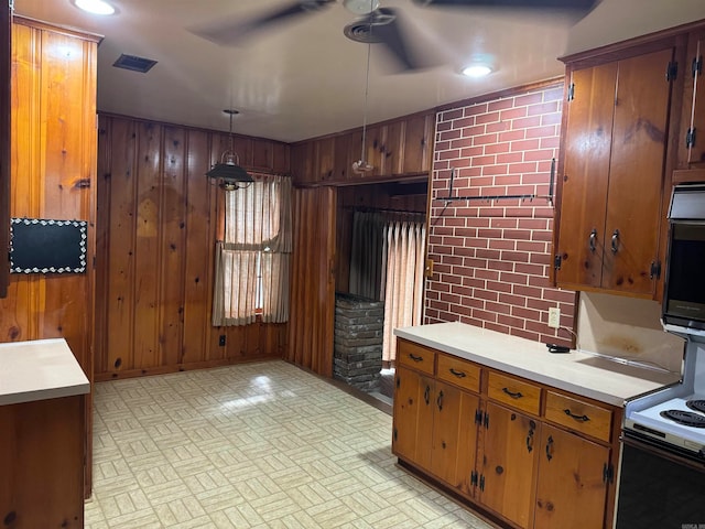 kitchen with pendant lighting, wood walls, oven, and ceiling fan