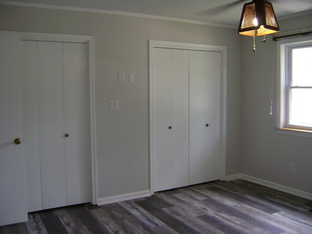 unfurnished bedroom featuring crown molding and dark wood-type flooring