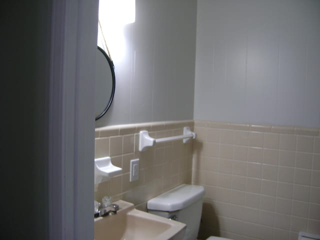 bathroom featuring sink, tile walls, and toilet