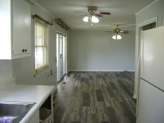 kitchen with ceiling fan, white cabinets, white refrigerator, ornamental molding, and dark wood-type flooring