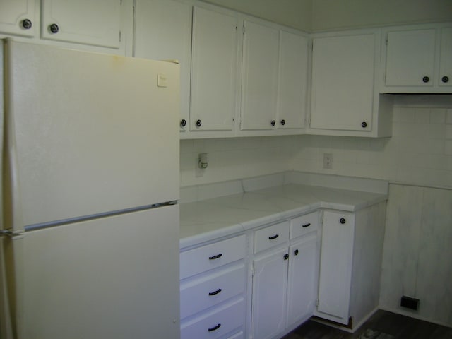 kitchen featuring white cabinetry, white fridge, and backsplash