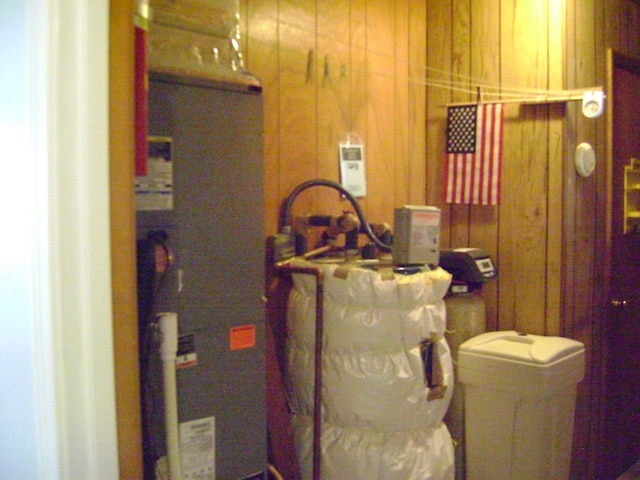 laundry room with wood walls and water heater