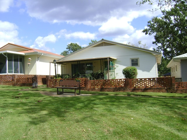 rear view of house with a sunroom and a lawn