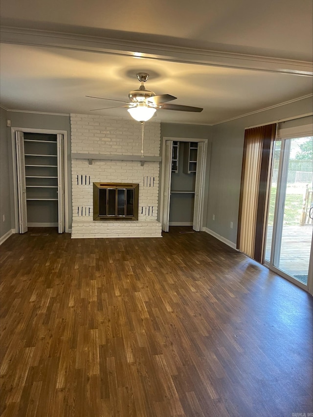 unfurnished living room with ceiling fan, a brick fireplace, dark hardwood / wood-style flooring, and crown molding