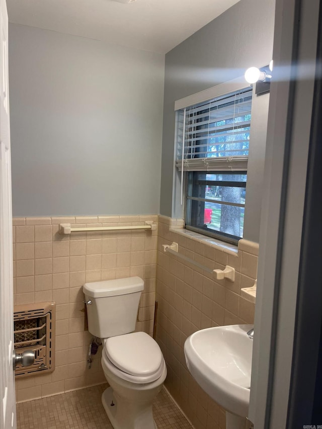 bathroom with heating unit, tile walls, sink, tile patterned floors, and toilet