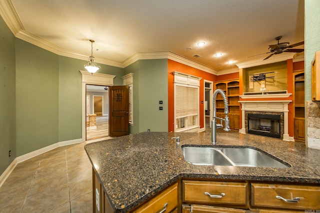 kitchen with ceiling fan, pendant lighting, sink, a fireplace, and crown molding