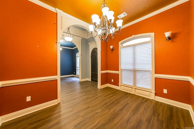 empty room featuring a chandelier, a textured ceiling, dark hardwood / wood-style floors, and crown molding