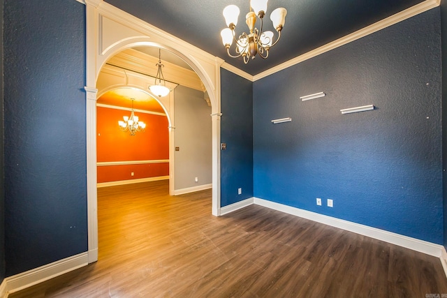 empty room featuring an inviting chandelier, hardwood / wood-style floors, and crown molding