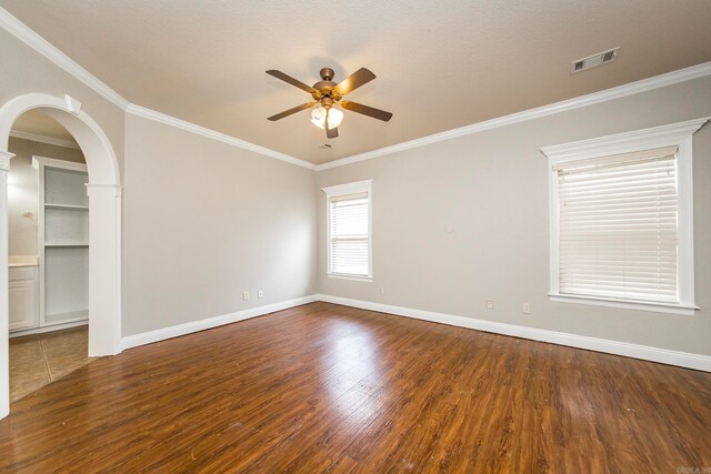 spare room with ceiling fan, ornamental molding, a textured ceiling, and dark wood-type flooring