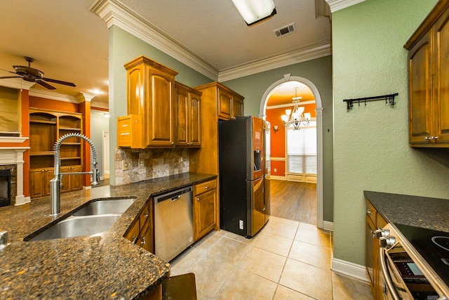 kitchen featuring ornamental molding, sink, backsplash, stainless steel appliances, and ceiling fan with notable chandelier