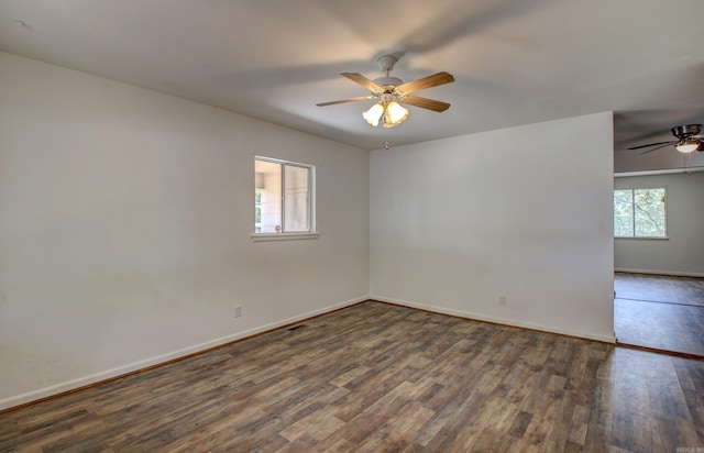 empty room featuring a healthy amount of sunlight, dark wood-type flooring, and ceiling fan