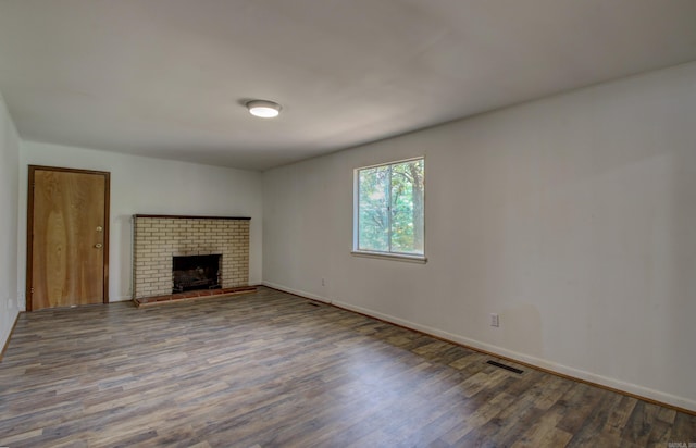 unfurnished living room with hardwood / wood-style flooring and a brick fireplace