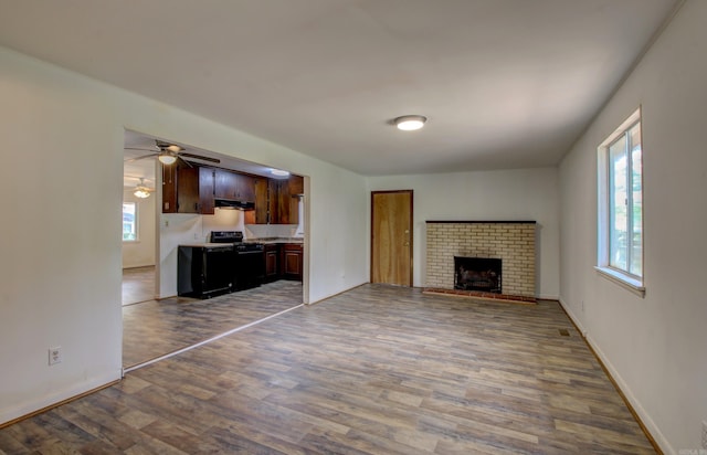 unfurnished living room with a brick fireplace, ceiling fan, and hardwood / wood-style floors