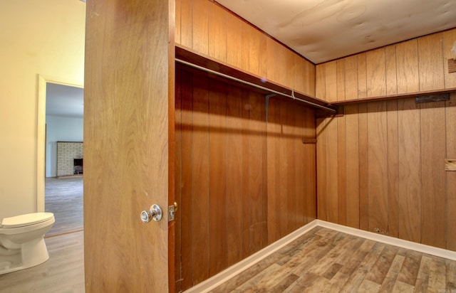 spacious closet featuring a brick fireplace and light wood-type flooring