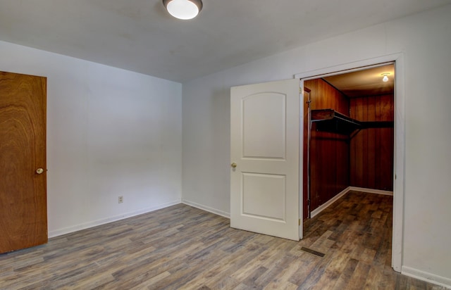 unfurnished bedroom featuring a spacious closet, a closet, and dark hardwood / wood-style flooring