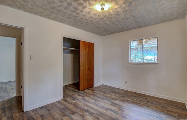 unfurnished bedroom with a textured ceiling, dark wood-type flooring, and a closet